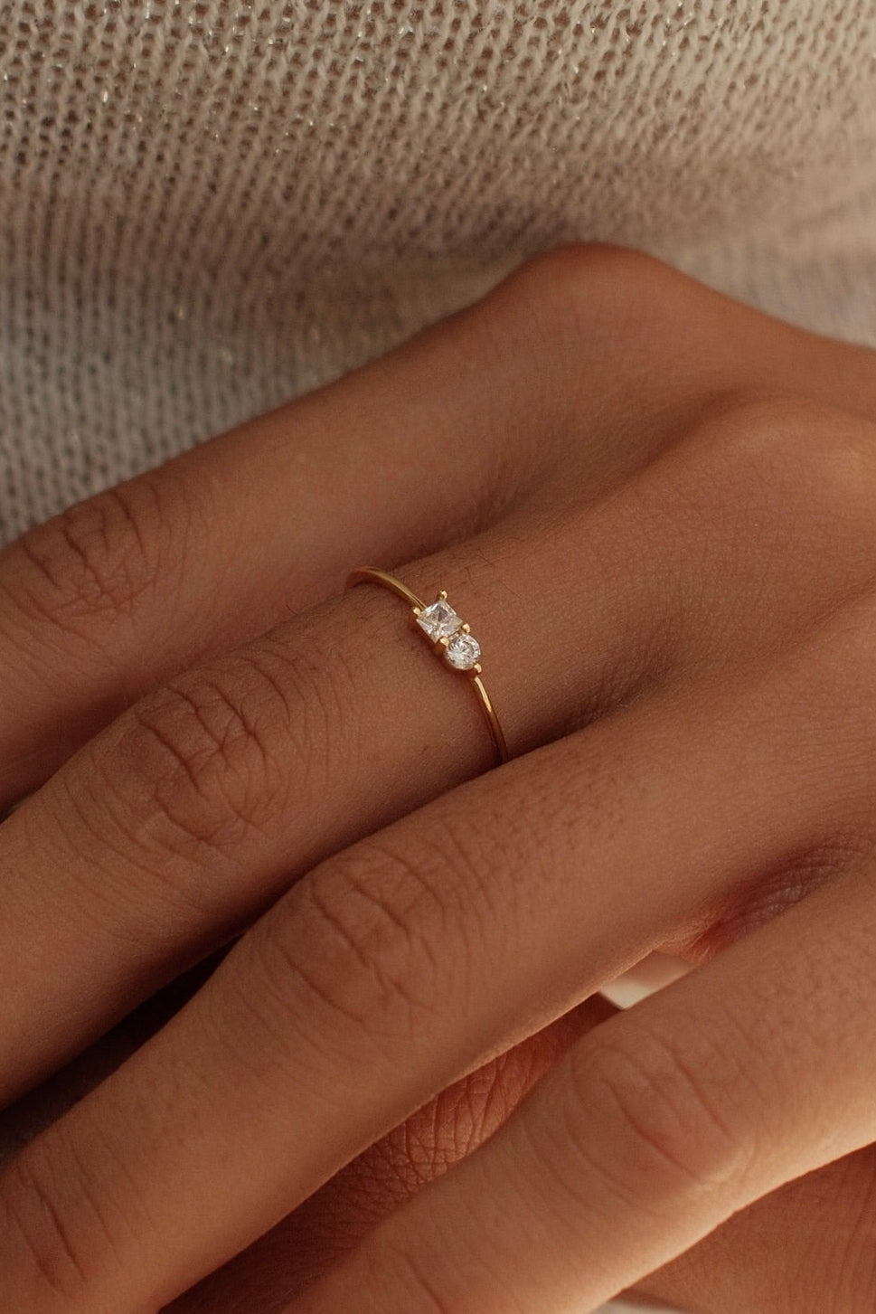 Close-up of two hands with a ring on a neutral background