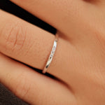 Hand wearing two silver rings with a blurred background