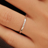 Hand wearing two silver rings with a blurred background