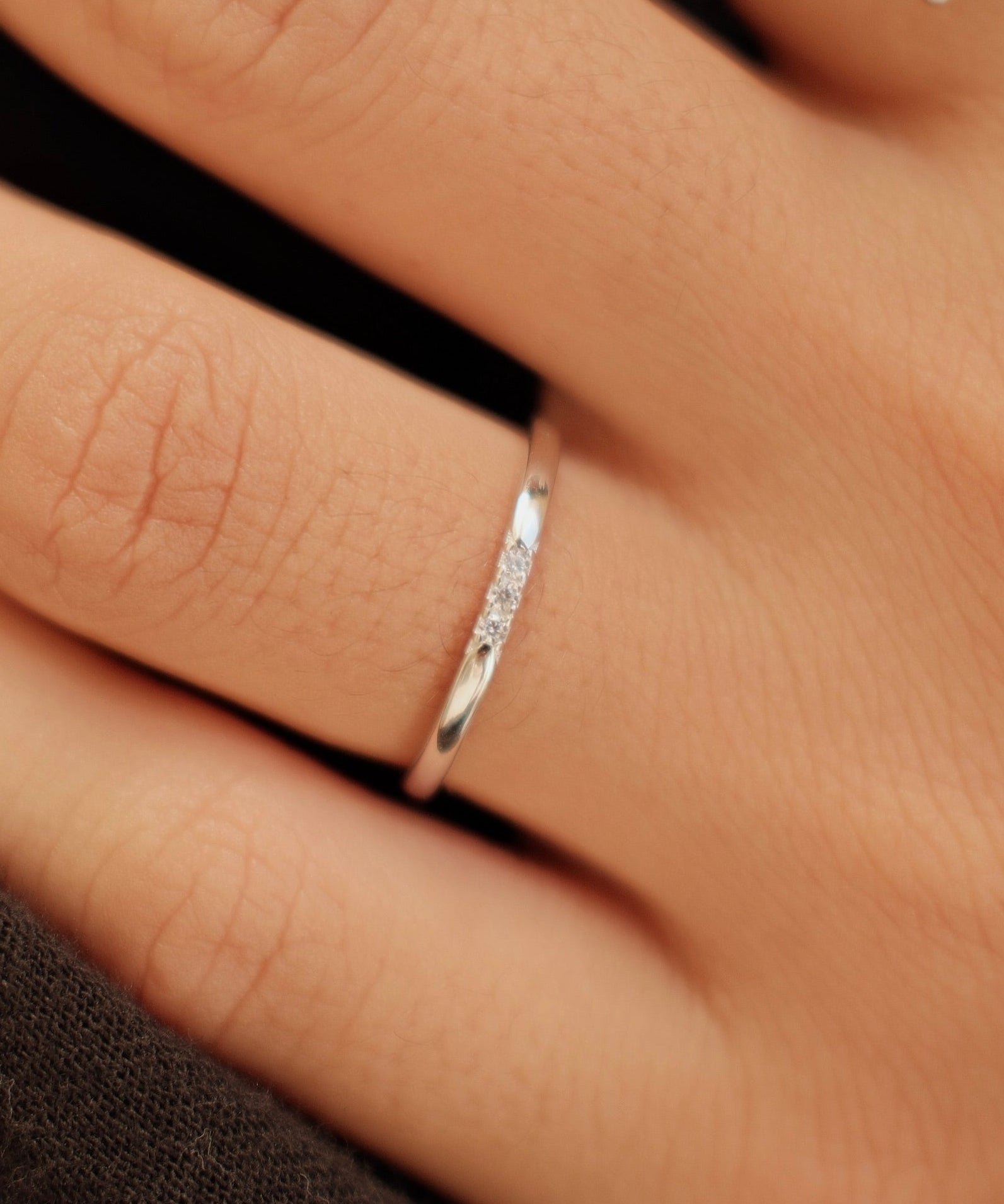 Hand wearing two silver rings with a blurred background