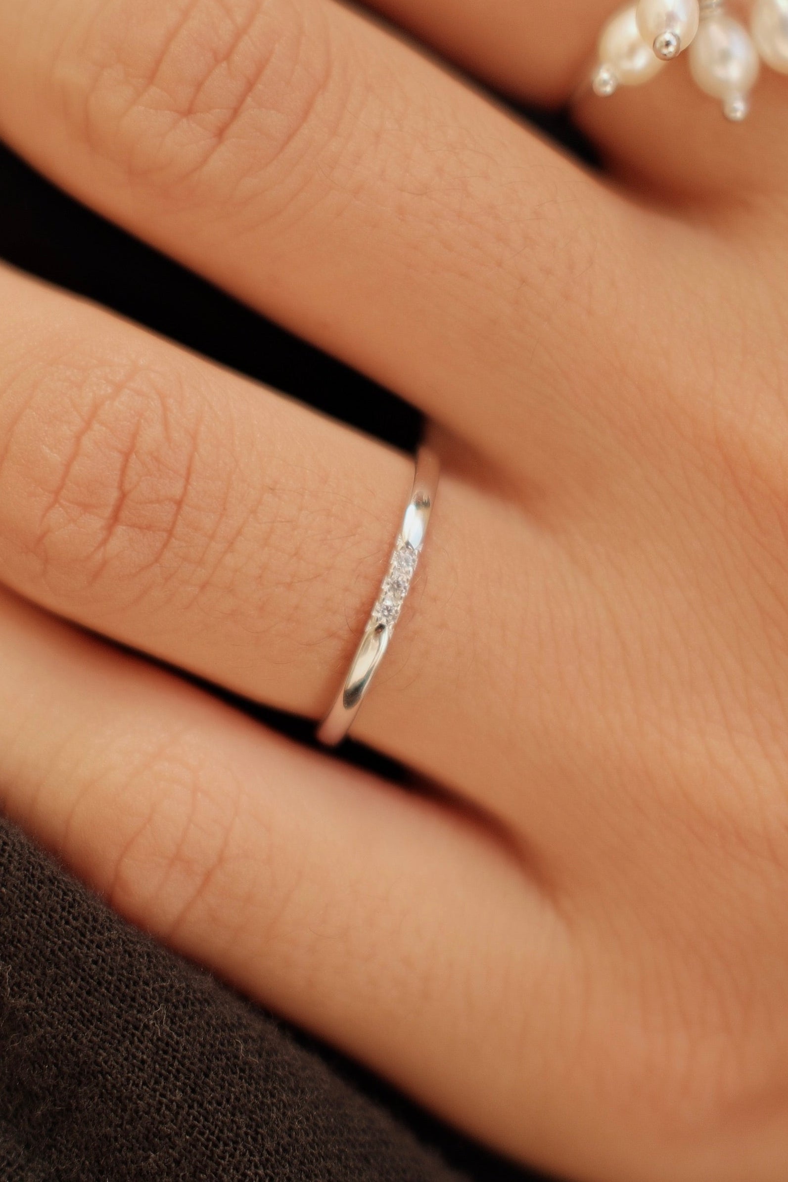 Hand wearing two silver rings with a blurred background