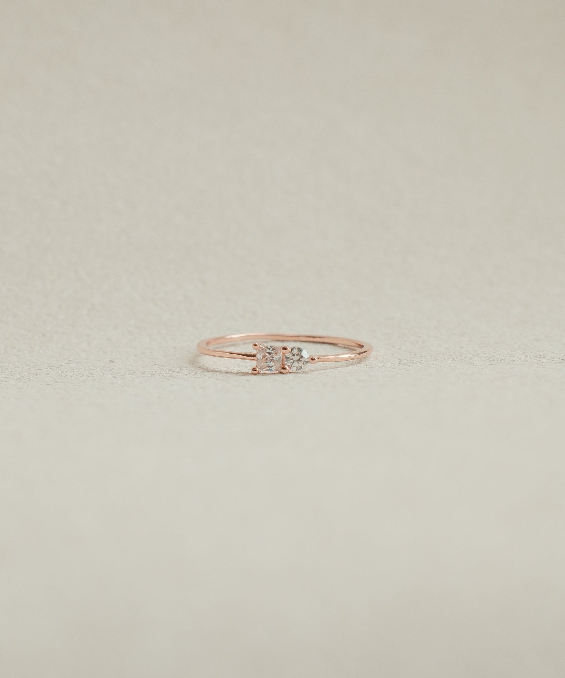 Rose gold ring with a diamond on a beige background