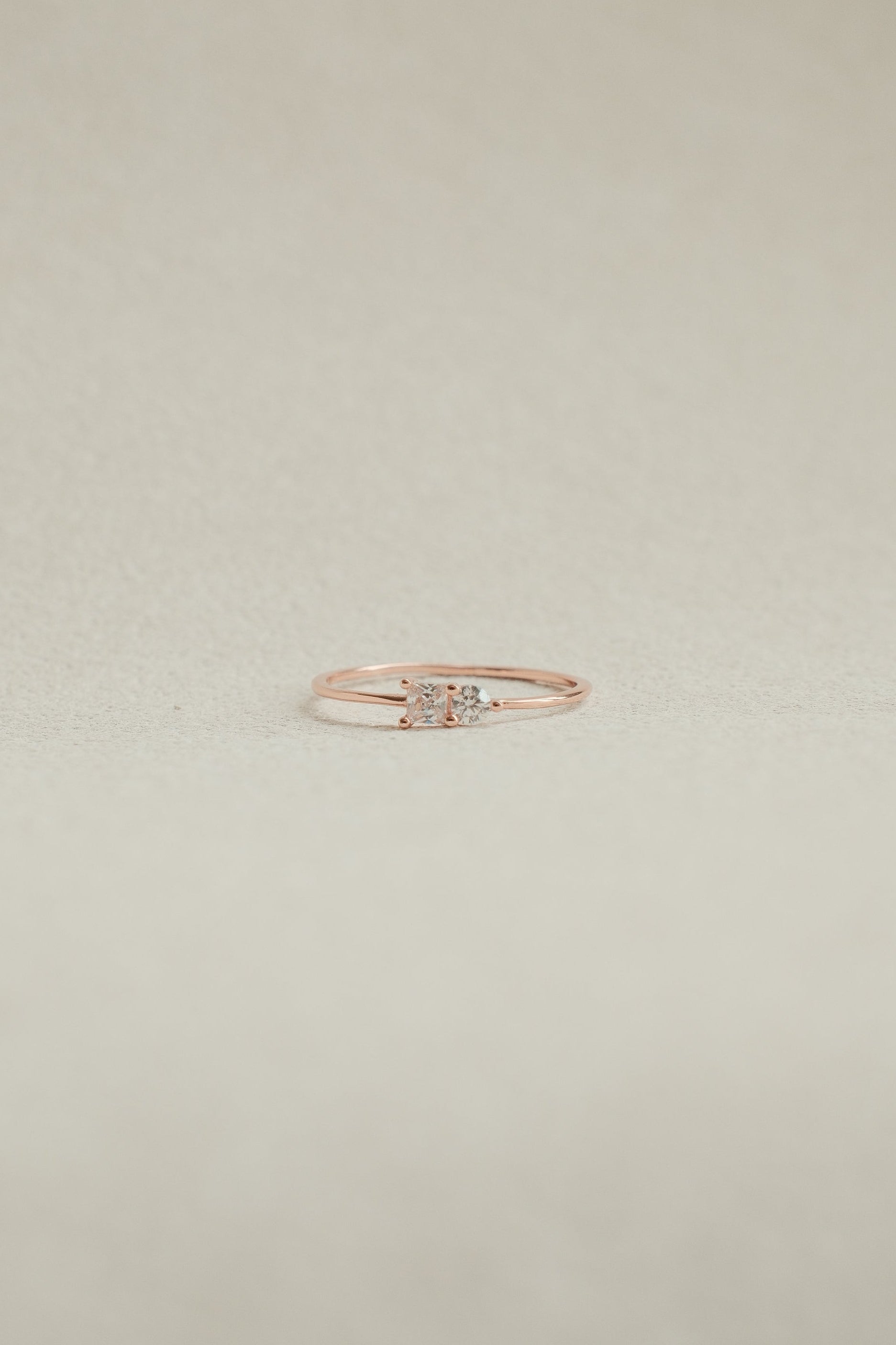 Rose gold ring with a diamond on a beige background