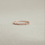Rose gold ring with small diamonds on a light beige background