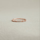 Rose gold ring with small diamonds on a light beige background