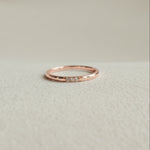 Rose gold ring with small diamonds on a light beige background