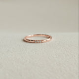 Rose gold ring with small diamonds on a light beige background